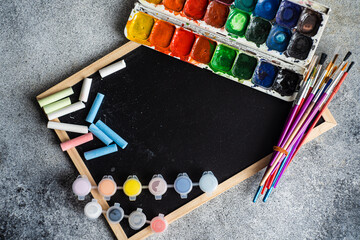 Composition of watercolors with brushes and blackboard with chalks