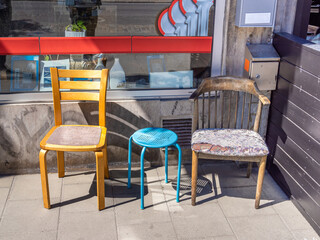 A group of old used and partially broken chairs from different materials.