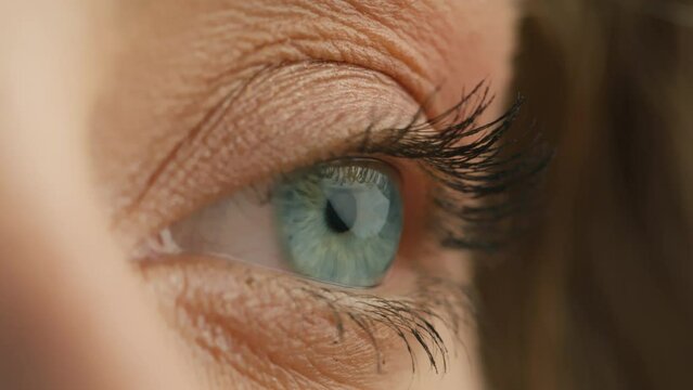 Side view macro close up of light blue female eye opening. Fashion model, natural day makeup mascara on eyelashes. Blue iris natural beauty looking aside. Opening and closing blue eyes beautiful girl