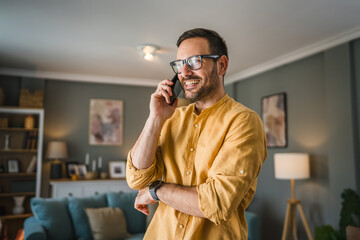 One adult man with eyeglasses stand at home use mobile phone talk