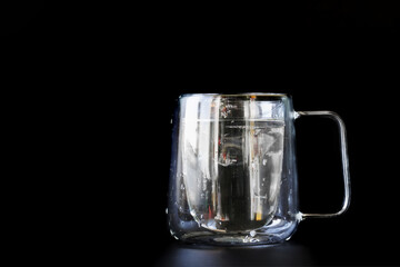 Water-filled trendy double-walled glass mug on a black background. Photo. Copy space