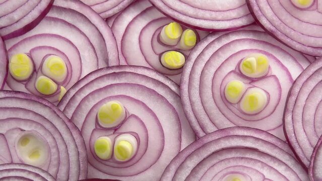 Sliced red onion rotates as background for cooking show, restaurant or food video. Sliced shallot rings close-up. Top view of food healthy background with vegetable of rich vitamin