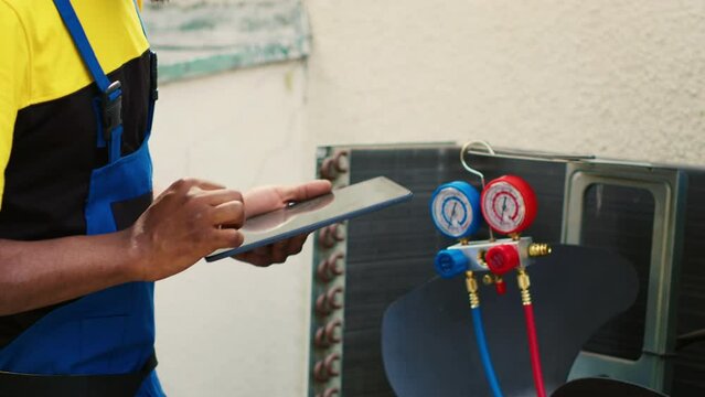 Certified technician doing hvac system inspection of freon levels and necessary fixes to prevent major breakdowns. Competent mechanic troubleshooting air conditioner, writing findings on clipboard