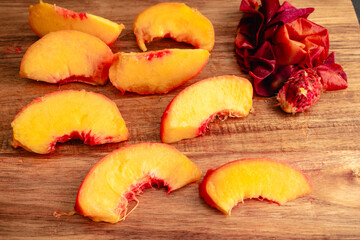 Peeled and Sliced Peach on a Wood Cutting Board: Close-up view of peeled and pitted peach cut into slices on a wood table