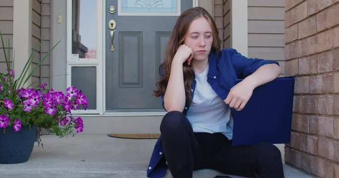 Sad Student Sitting on Steps Outside of a Suburban House
