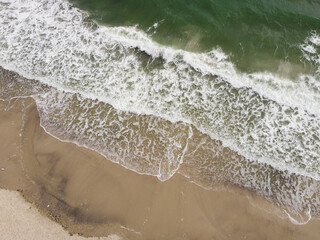 a stunning aerial view of the sea, with waves breaking against a sandy beach. 