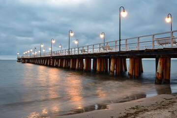 Obraz premium Dark morning landscape over the Baltic Sea. Popular pier in Gdynia Orlowo, Poland. Photo taken with long exposure time.