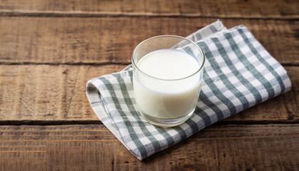 glass of milk with napkin on old wooden table