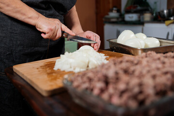 Close up of unrecognizable latin woman chopping onion and meat for filling chilean baked empanadas