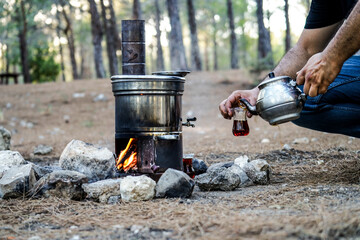 Tea urn in the camp, man pouring tea to glass from teapot