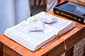 a pair of wedding rings on top of an open bible - Powered by Adobe