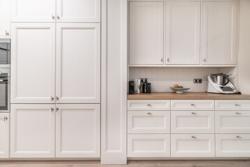 Front wall of a kitchen covered with white wooden cabinets