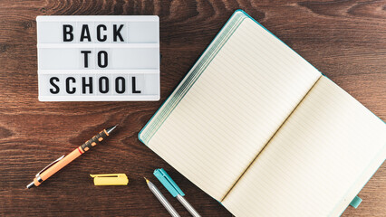 Back to school concept. School supplies on wooden background. Back to school lettering on white letter board. Copy space for text. Selective focus included