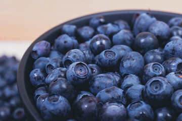 Fresh blueberries in black bowl. Bowl filled with ripe blueberries. Close-up shot.