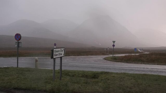 Footage of a road sign pointing towards Glen Etive on a rainy day in the Scottish Highlands