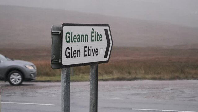 Footage of a road sign pointing towards Glen Etive on a rainy day in the Scottish Highlands