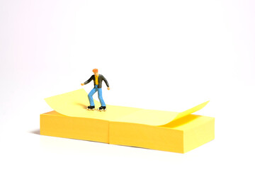 Creative miniature people toy figure photography. Sticky notes installation. A boy roller skater...