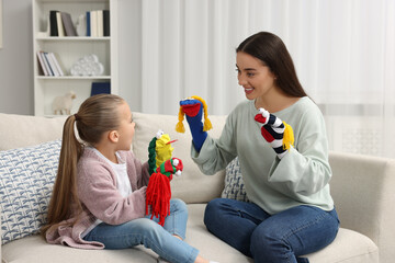 Happy mother and daughter playing with funny sock puppets together at home