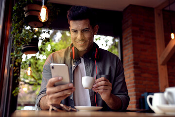 Man using smartphone with facial recognition system in cafe. Security application scanning his face...