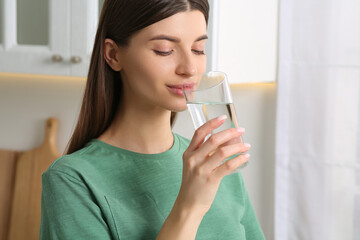 Healthy habit. Woman drinking fresh water from glass indoors