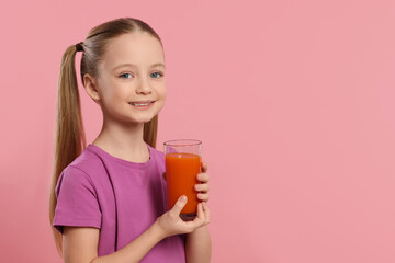 Cute little girl with glass of fresh juice on pink background, space for text