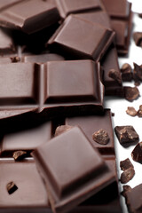 Pieces of delicious dark chocolate bar on white background, closeup