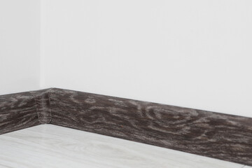 Black wooden plinth with connector on laminated floor near white wall indoors, closeup