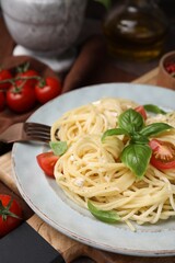 Delicious pasta with brie cheese, tomatoes and basil leaves on table, closeup