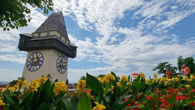 Cityscape of old town of Graz and the Clock Tower (Grazer Uhrturm), famous tourist attraction in Steiermark, Austria, in cloudy summer day in 4k
