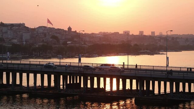 Golden hours sunset time panoramic view in Istanbul Golden Horn with Unkapanı bridge, cars, buildings, Turkish flags. 