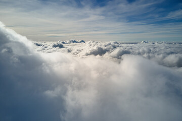 Aerial view from airplane window at high altitude of earth covered with puffy cumulus clouds...