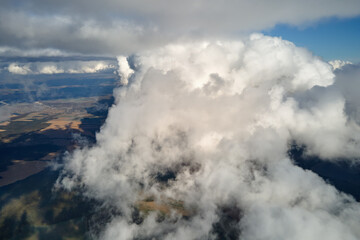 Aerial view from airplane window at high altitude of earth covered with puffy cumulus clouds forming before rainstorm