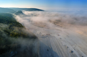 Aerial view of open pit mining of limestone materials for construction industry with excavators and dump trucks