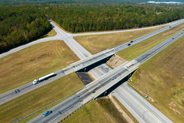 View from above of busy american highway with fast moving traffic between woods. Interstate...