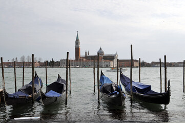 Fototapeta na wymiar Gondolas And Wooden Pillars On The Grand Canal Near The Church Of San Giorgio Maggiore In Venice, Italy