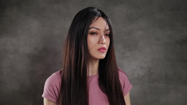 Young Asian woman in a studio looks at the camera - extreme slow motion