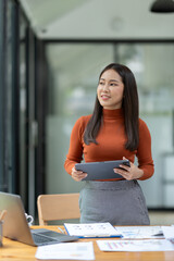 Asian businesswoman using tablet, laptop at modern office to research, record, to make account analysis report, real estate investment data. Division of paperwork. Finance and tax system concept.