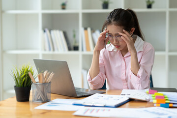 Cropped image of asian businesswoman analyzing paperwork using laptop to actively search for information tense expressions at the office.