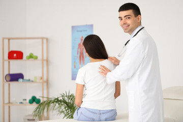 Obraz premium Male doctor checking posture of young woman in clinic