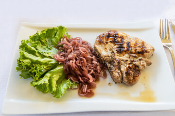 Simple serving portion of delicious Italian grilled pork served with salad and condiments in Tuscany Italy