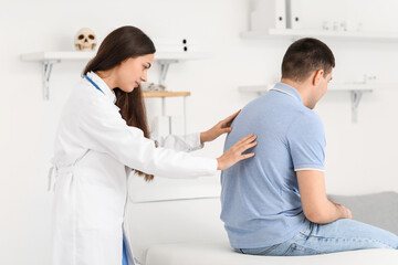 Obraz premium Female doctor checking posture of young man in clinic