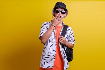 Shocked surprise young tourist man in summer clothes, hold backpack, cover his mouth with hand when seeing big discount on holiday trip promotion. Tour and travel business concept