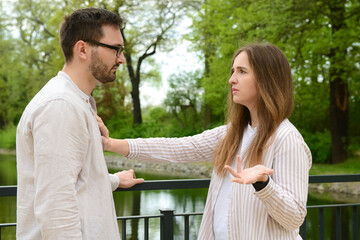 Beautiful couple arguing on bridge in park