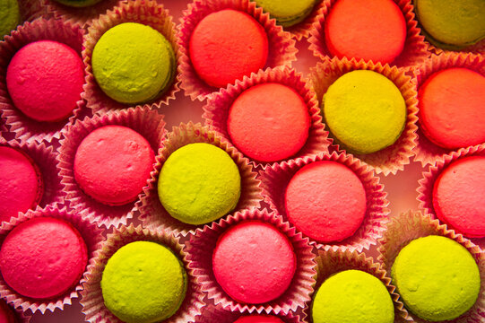 pink and yellow macaroons in pink wrappers arranged on a table