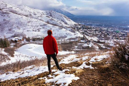 A young man in a red puffy jacket standing above Salt Lake City, Utah in winter