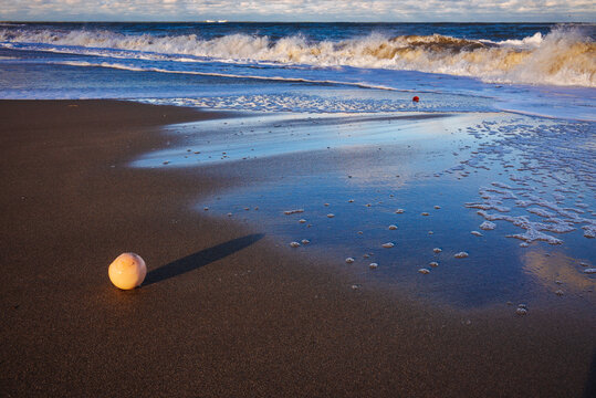 Glass fishing floats washed up along the beach at dawn with waves crashing in the distance