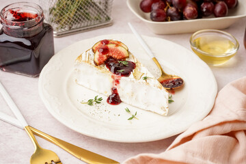Plate with tasty baked Camembert cheese on light background