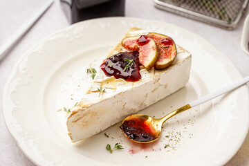 Plate with tasty baked Camembert cheese on light background