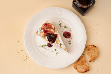 Plate with tasty baked Camembert cheese on yellow background