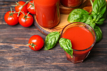 Glass of tasty tomato juice on black wooden background